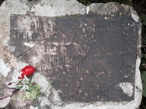 Cippo commemorativo dedicato a Dini, Meini e Rossi, con fiori deposti in ricordo.
