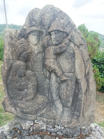 Monumento ai caduti con figure scolpite in pietra che rappresentano soldati e una figura femminile.