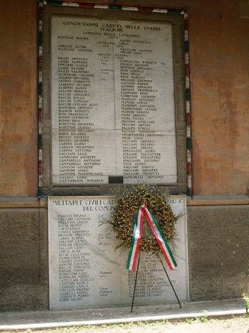 Lapide commemorativa ai caduti militari e civili di Brescello, con elenco dei nomi e omaggio floreale.