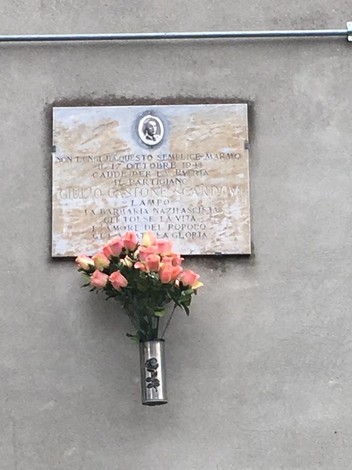 Lapide commemorativa a Scardovi con fiori, in ricordo di un evento significativo.