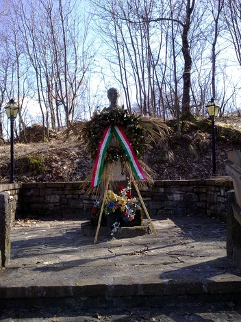 Monumento dedicato a Borghi e ai caduti in guerra, adornato con fiori e ghirlande, immerso nel verde.