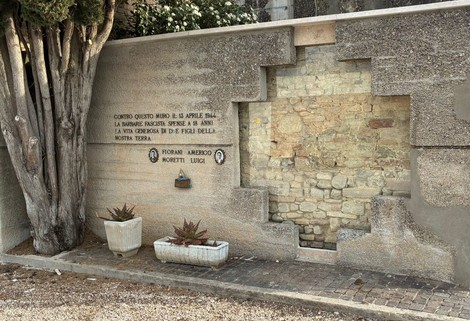 Memoriale dedicato a Fiorani e Moretti, con pietre a vista e piante ornamentali, situato in un ambiente sereno.