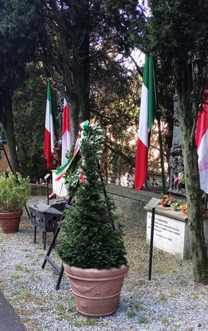Monumento agli Internati Militari Italiani circondato da cippi commemorativi e bandiere italiane.