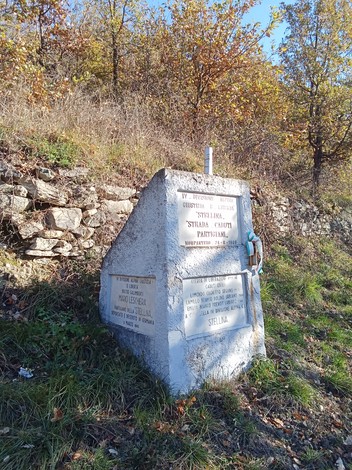 Monumento ai caduti per la Libertà, immerso nella natura, con iscrizioni commemorative su un basamento.