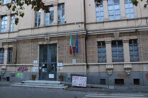 Edificio storico a Schiavon con decorazioni architettoniche, bandiere e graffiti visibili sulla facciata.