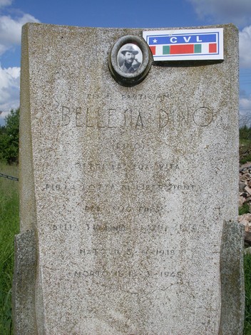 Cippo commemorativo a Bellesia, dedicato a un eroe locale, con dettagli decorativi e simboli patriottici.