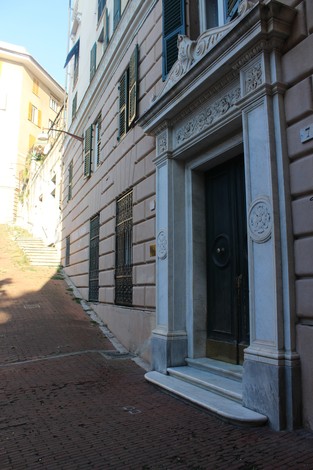 Ingresso di edificio storico su via lastricata con architettura elegante e dettagli architettonici.