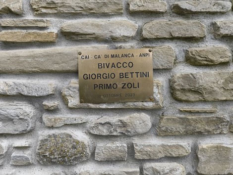Targa commemorativa intitolata a Giorgio Bettini e Primo Zoli, posizionata su una parete di pietra.
