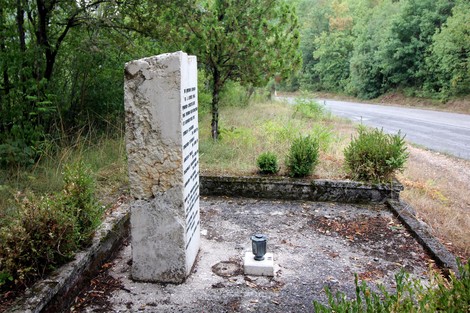 Cippo commemorativo dedicato ai partigiani uccisi a Colle di Postignano, immerso nella natura.