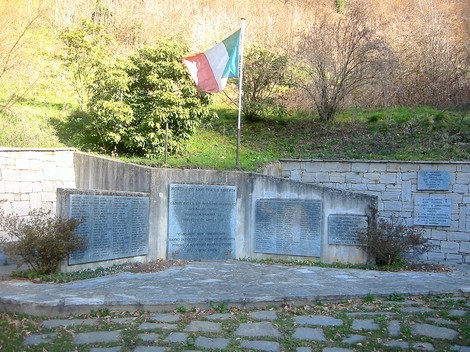 Monumento commemorativo ai caduti per la Libertà, con bandiera italiana e targhe commemorative.