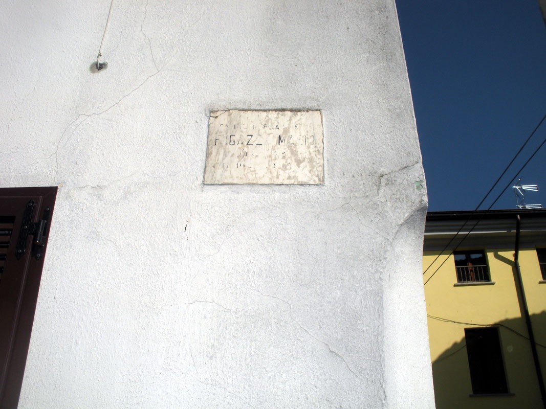 Lapide commemorativa dedicata a Fugazza Mario su un muro bianco.