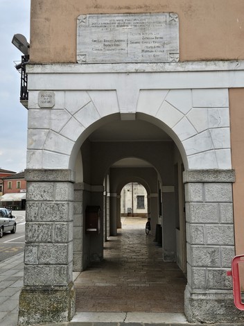 Lapide commemorativa in un portico, dedicata ai caduti per la liberazione, visibile su un muro.