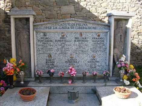 Monumento commemorativo ai caduti partigiani di Felina, decorato con fiori e iscrizioni in memoria dei martiri.