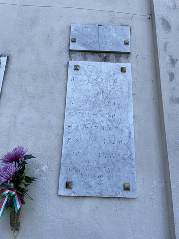 Lapidi commemorative dei caduti di Savonera, con fiori e decorazioni tricolori.