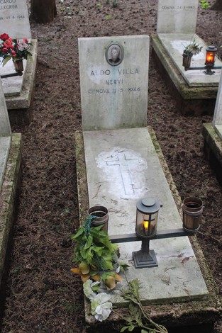 Tombe perpetue dedicate ai caduti, con fiori e candele, in un ambiente naturale sereno.