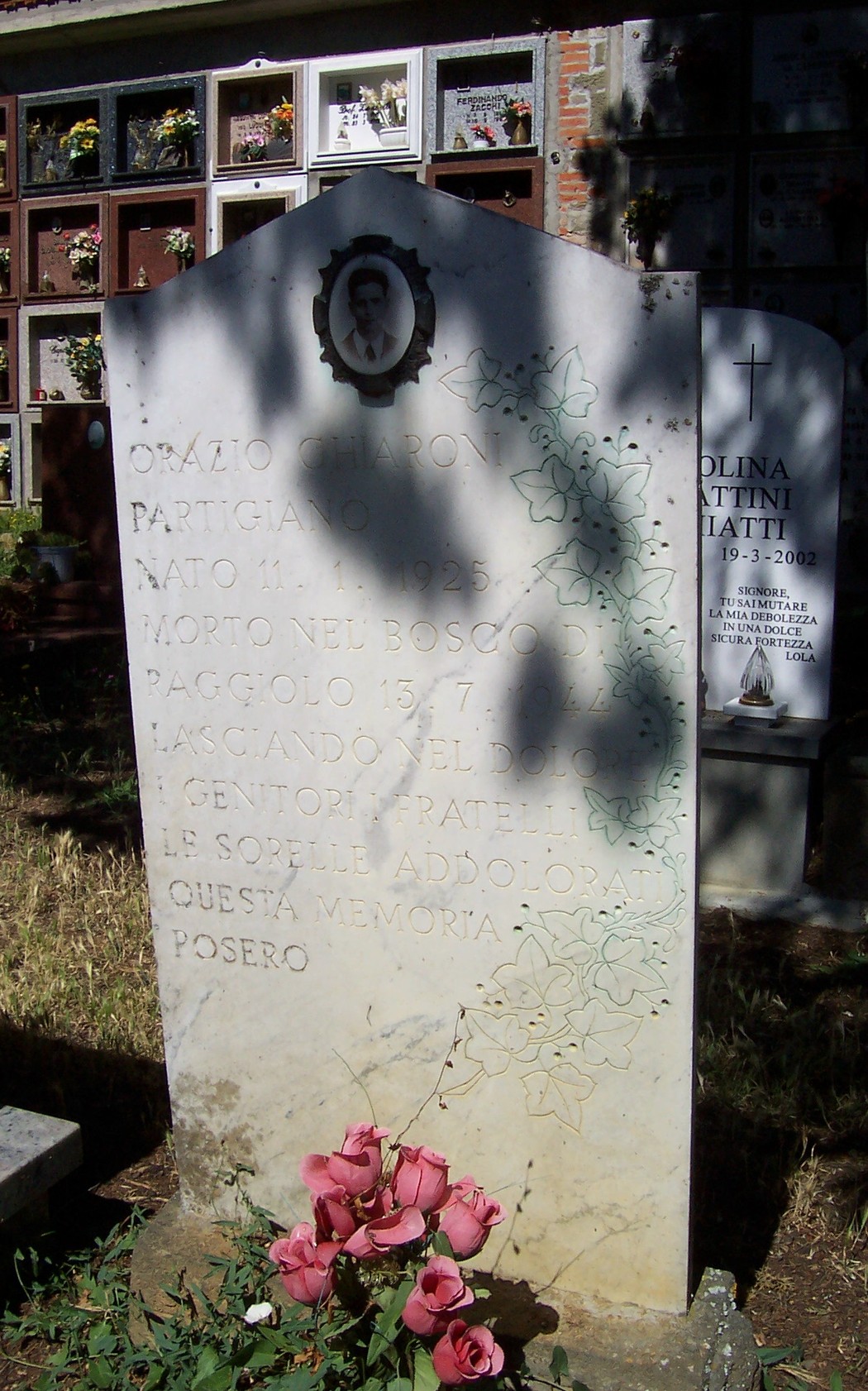 Sepolcro di Chiaroni, dedicato a un partigiano, con scritte commemorative e rose ai suoi piedi.