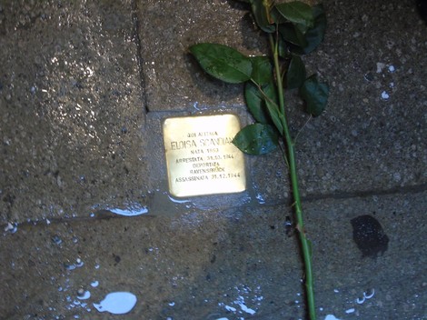 Pietra d'inciampo dedicata a Eloisa Scavina, con una rosa posta accanto, su una pavimentazione.