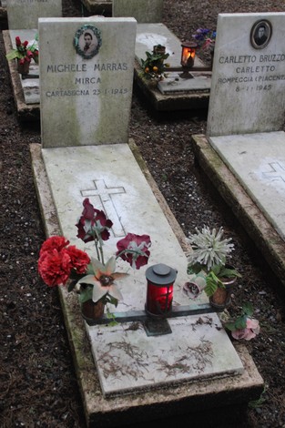 Tombe decorate con fiori e candele in memoria dei caduti per la libertà, simbolo di rispetto e commemorazione.