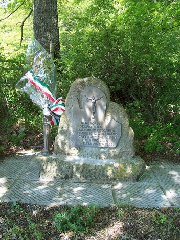 Monumento a Ceccattini, commemorazione situata in un'area verde, con un basamento in pietra e decorazioni floreali.
