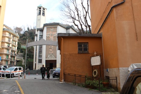 Immagine che mostra la lapide ai caduti della Croce bianca, posizionata in un contesto urbano con edifici circostanti.