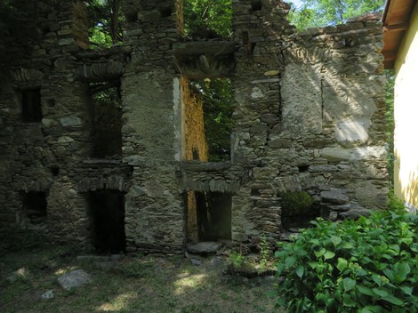 Rovine di una struttura in pietra circondata da vegetazione, evidenziando la sua antica architettura.