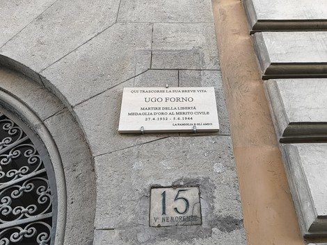 Lapide commemorativa di Ugo Forno, martire della libertà, situata in un edificio storico.