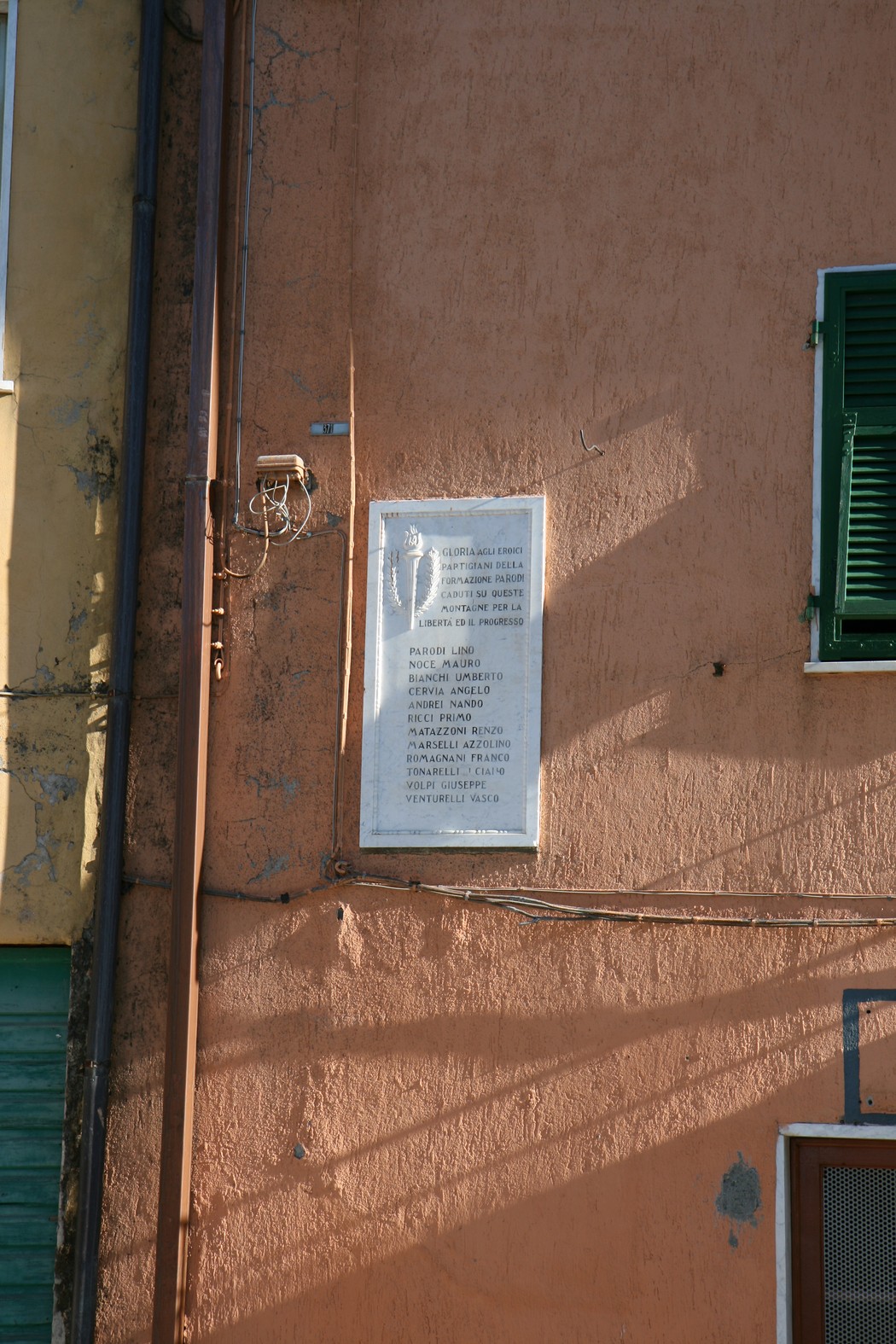 Lapide commemorativa dedicata alla brigata Parodi, affissa su un muro colorato.
