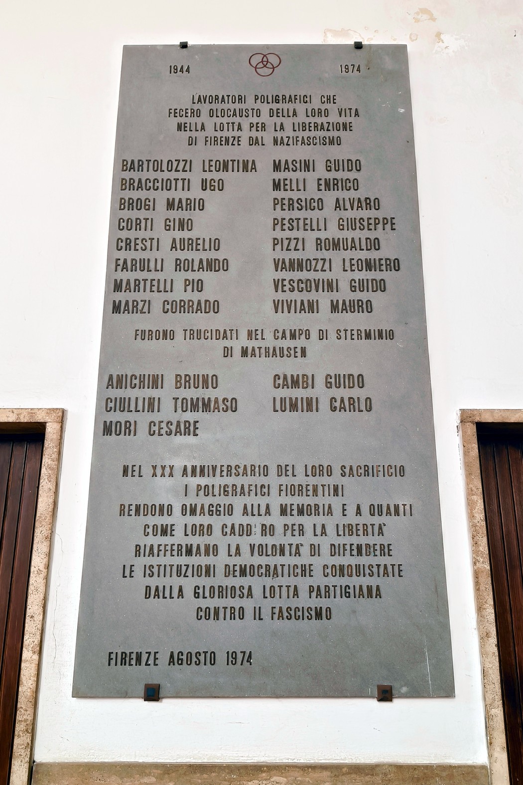 Lapide commemorativa dedicata ai poligrafici caduti per la libertà, con nomi e date storiche.