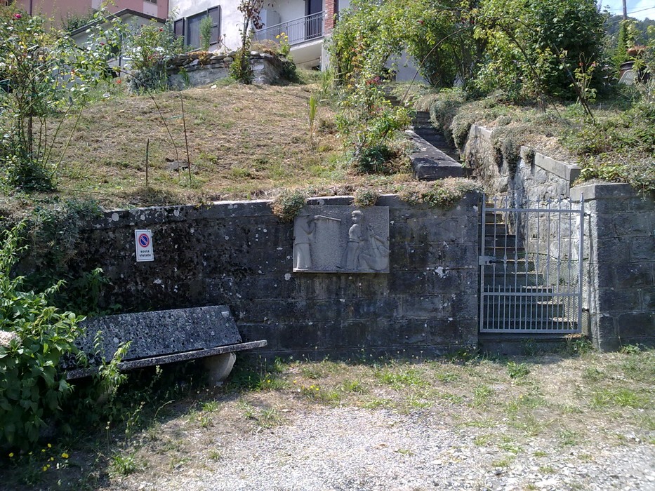 Lapide commemorativa dedicata ai fucilati di Ramiseto, situata in un ambiente naturale e tranquillo.