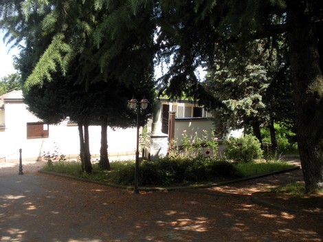 Cippo commemorativo dedicato ai caduti, circondato da alberi e vegetazione a Rocca de' Giorgi.