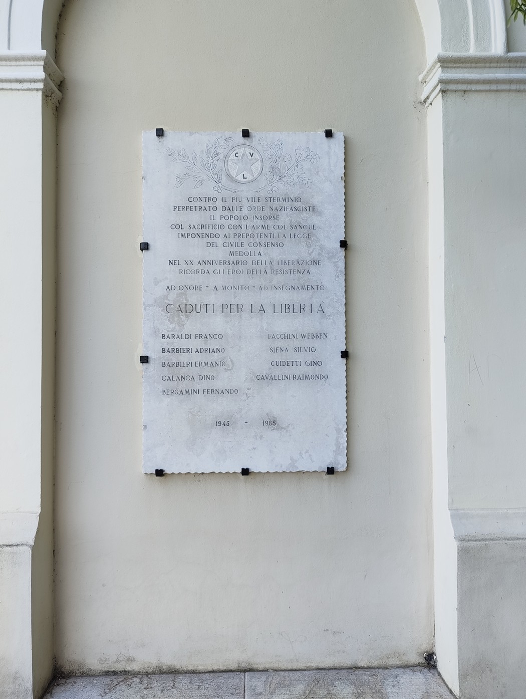 Lapide commemorativa dedicata ai caduti per la libertà, incastonata in un muro.