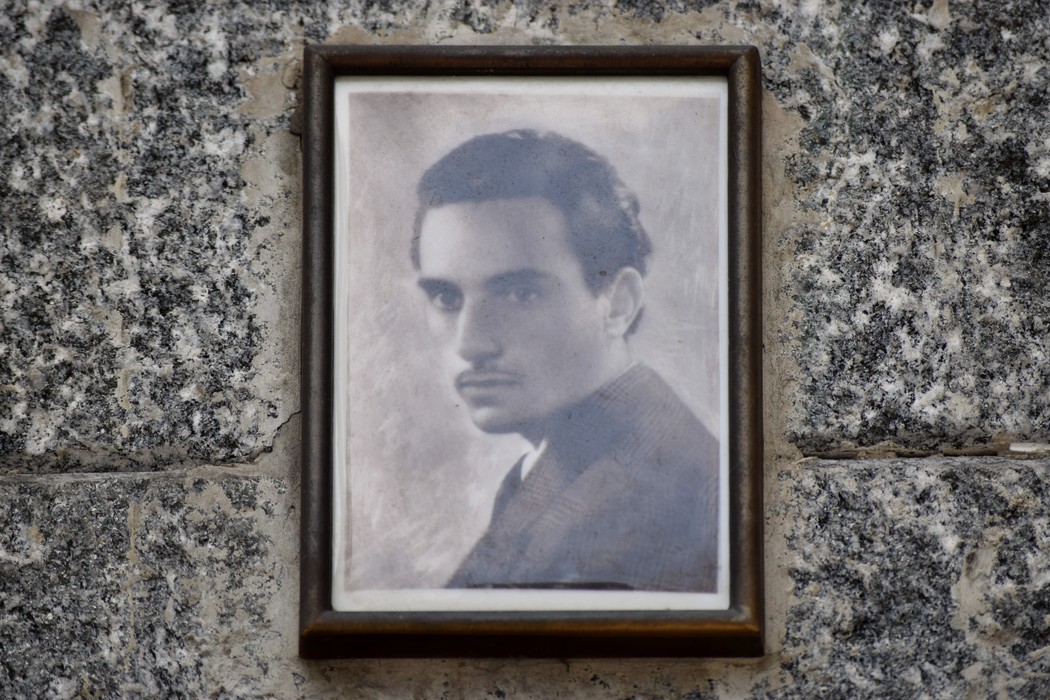 Ritratto in bianco e nero di un giovane affisso su una lapide in marmo.