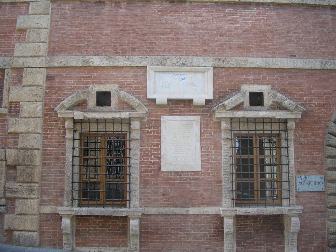 Lapide commemorativa dedicata ai caduti della Resistenza, situata su un muro di mattoni.