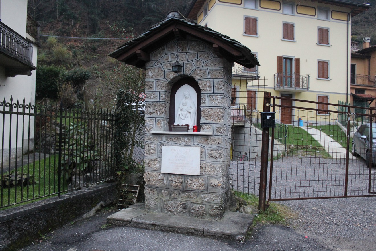 Tabernacolo in pietra con statua al suo interno, situato in un'area residenziale appartata.