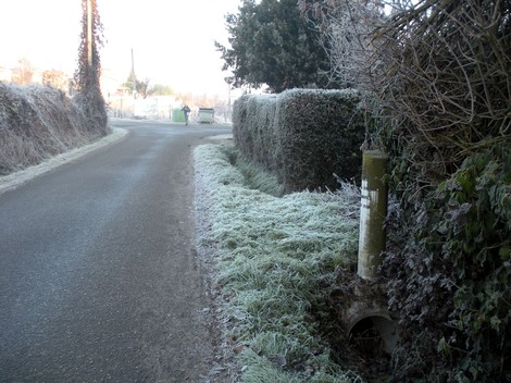 Cippo a Yoberdoff lungo una strada invernale, circondato da vegetazione ghiacciata.