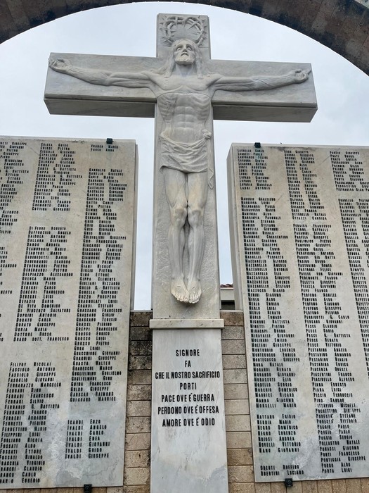 Monumento al sacrificio nel "Campo della Gloria", con croce e pannelli commemorativi di caduti in guerra.
