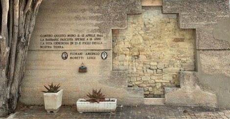 Memoriale dedicato a Fiorani e Moretti, con scritte commemorative e piante ornamentali.