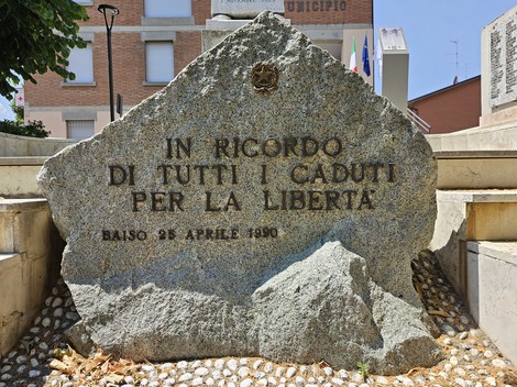 Lapide commemorativa in pietra dedicata ai caduti per la libertà, situata in un'area pubblica.