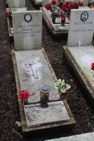 Tombe di guerra decorate con fiori, commemorano i caduti per la Libertà in un cimitero silenzioso.