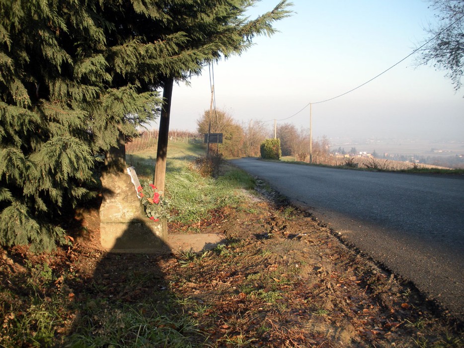 Cippo a Guagni situato lungo una strada panoramica, circondato da alberi e un paesaggio rurale.