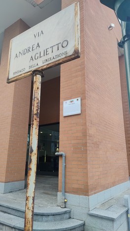 Targa di via Andrea Aglietto, con un design vintage e superficie arrugginita, che indica la strada e il suo significato storico.