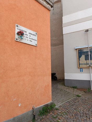 Lapide commemorativa su una parete in un angolo di Canavese, tra edifici storici.