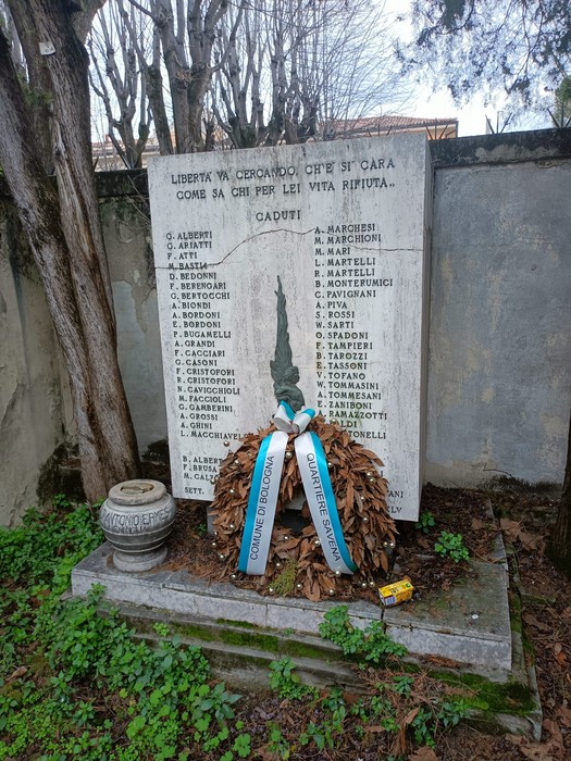 Lapide commemorativa in onore dei caduti per la Libertà, decorata con un mazzetto di foglie e nastri.