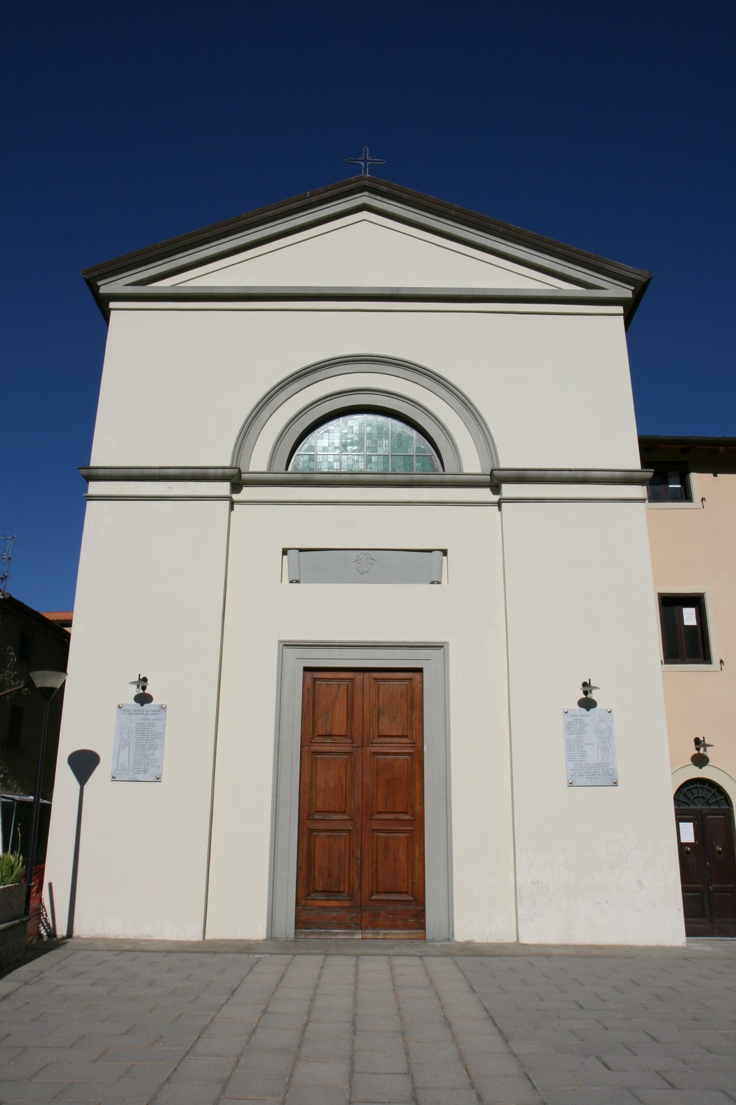 Lapide commemorativa ai caduti di Montalbano, situata davanti a un edificio sacro, cielo blu sullo sfondo.