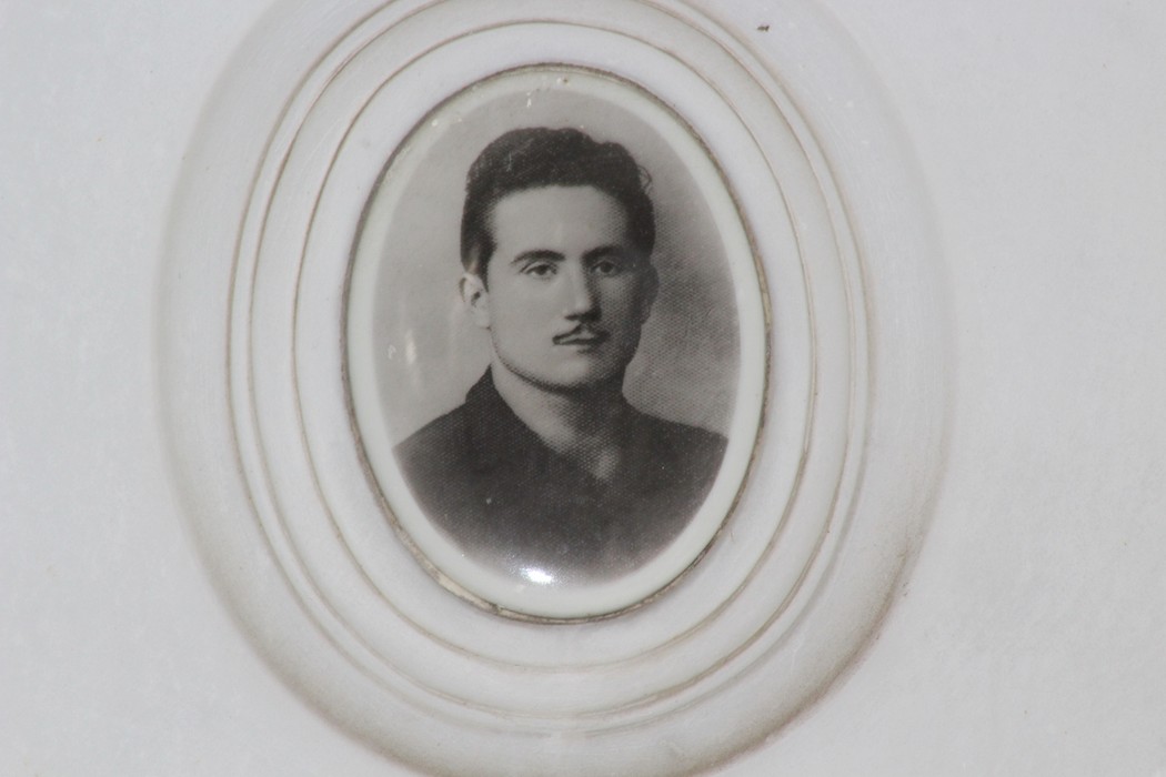 Ritratto in bianco e nero incastonato, raffigurante un uomo con baffi e sguardo serio, evocando la memoria partigiana.