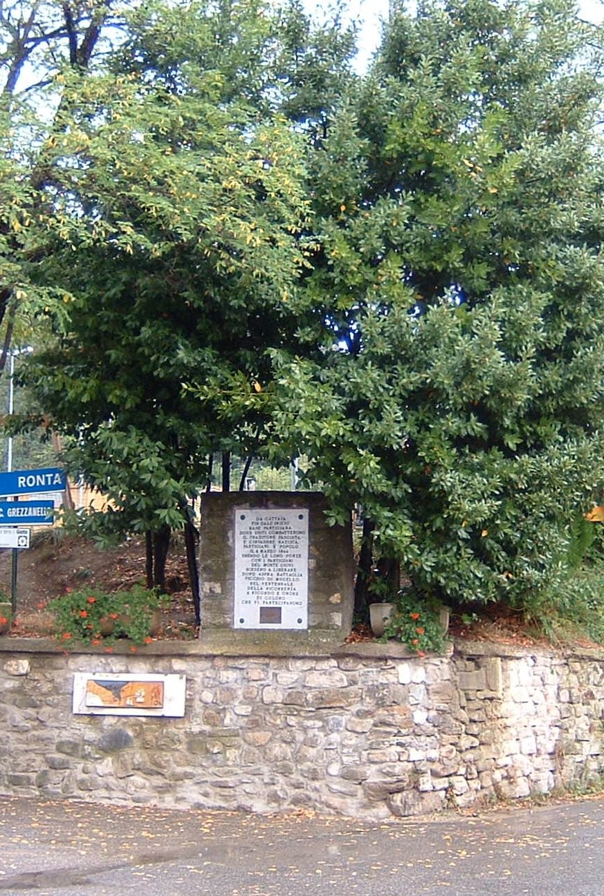 Lapide di Gattaia, monumento commemorativo tra alberi e muratura, immerso nella natura.