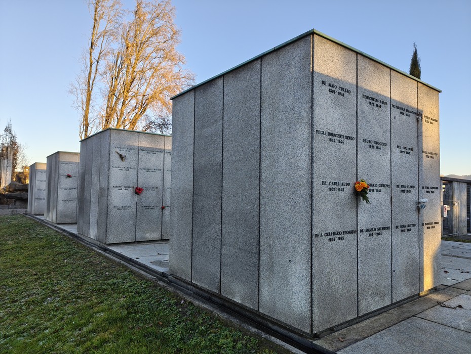 Campo della Gloria con monumenti funerari in pietra, delimitato da alberi e un cielo sereno.