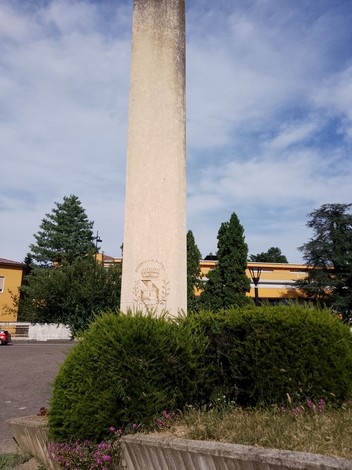 Monumento alla Resistenza, obelisco con dettagli decorativi, circondato da verde e alberi.