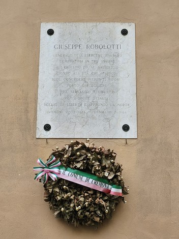 Lapide commemorativa dedicata a Giuseppe Robolotti, con corona di fiori e nastro tricolore.