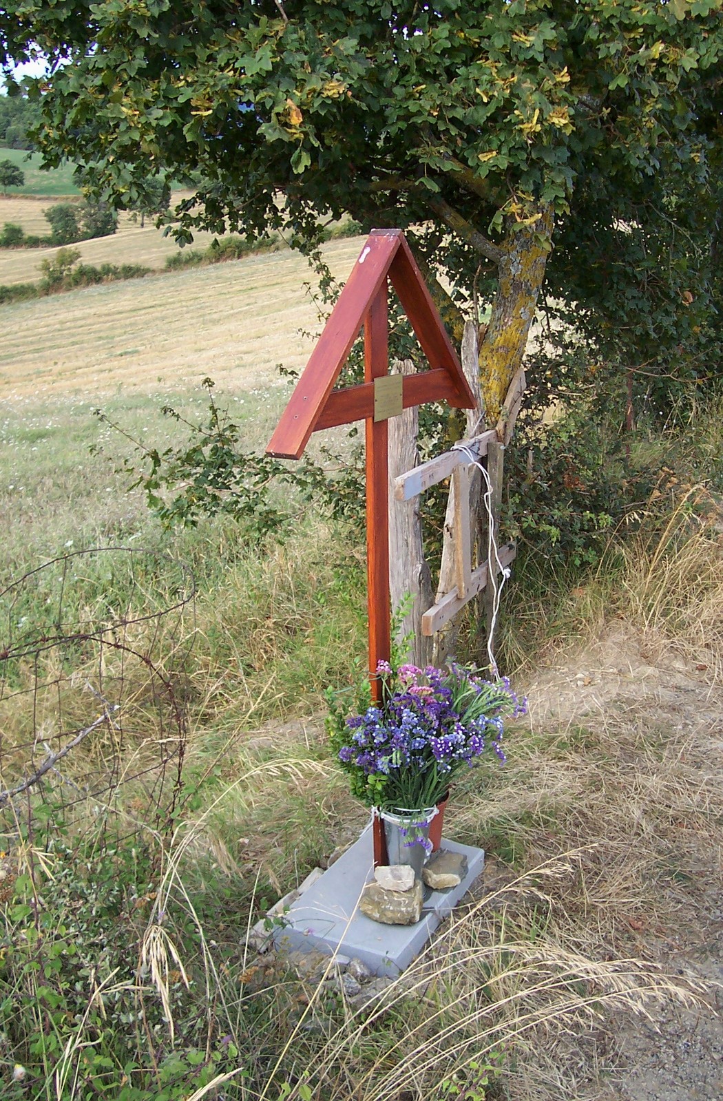 Croce commemorativa ai caduti di Terranieri, circondata da fiori e natura, simbolo di memoria e rispetto.